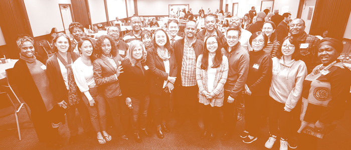 A group of 20 people of multiple races together in a conference room